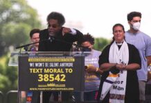 Speaker at outdoor rally gestures from a podium