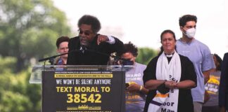 Speaker at outdoor rally gestures from a podium