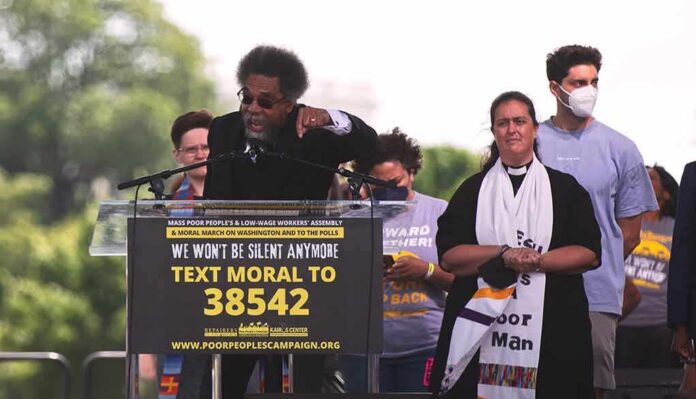 Speaker at outdoor rally gestures from a podium
