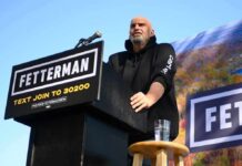 Fetterman Torches ‘Orgy Of Socialism’ Speaker at outdoor rally standing at podium with microphone