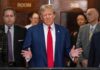 Trumpâs Face Comes to Americaâs Money A public figure speaking at a press conference with a group of people in the background