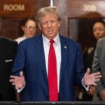 Trump’s Face Comes to America’s Money A public figure speaking at a press conference with a group of people in the background