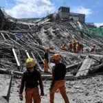 Tsunami Alert After Monster Quake Rescue workers survey collapsed building debris