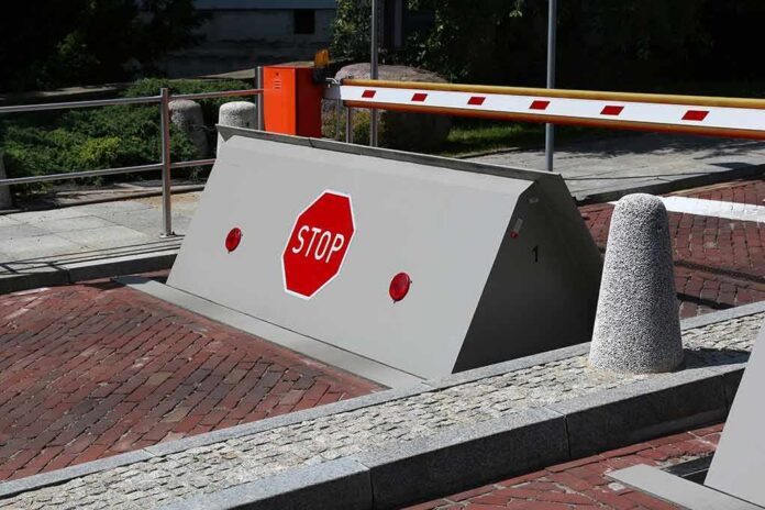 shutterstock_619363979 Rising road blocker with stop sign at a security checkpoint