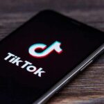 Is TikTok Pushing Kids Toward WAR?! smartphone displaying the TikTok app logo on screen