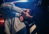 Police officer handcuffing person at night by patrol car