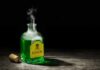 Glass bottle of green liquid labeled poison on wooden surface