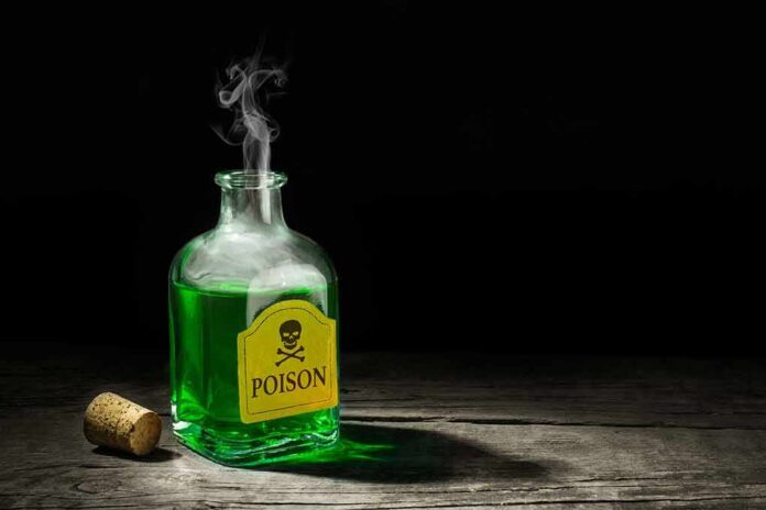 shutterstock_720129613 Glass bottle of green liquid labeled poison on wooden surface