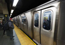 Subway train at platform with passengers inside and man waiting
