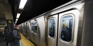 Subway train at platform with passengers inside and man waiting