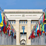 New UN Boss Sets Surprise Military Tone United Nations building with numerous national flags outside.