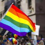DOJ Targets MLB Over Pride Caps Kim Kyung-tae with others waving a rainbow pride flag at a street parade