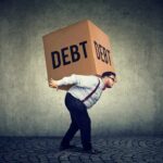 Man carrying a large box labeled debt on his back