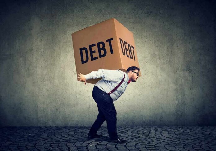 Man carrying a large box labeled debt on his back