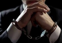 Disability Scam Exposed: Ski Trips, Caskets Businessperson in handcuffs with hands clasped