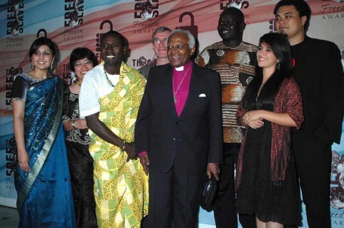 shutterstock_107645462 Desmond Tutu and Larry Burrows pose with a group at an awards event