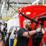 Dems Attempt To Imitate Trump’s MAGA Playbook Factory worker assembling red vehicle body on production line