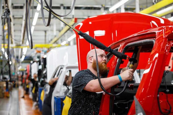 shutterstock_1158833029 Factory worker assembling red vehicle body on production line