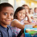 Smiling boy at a lunch table with classmates
