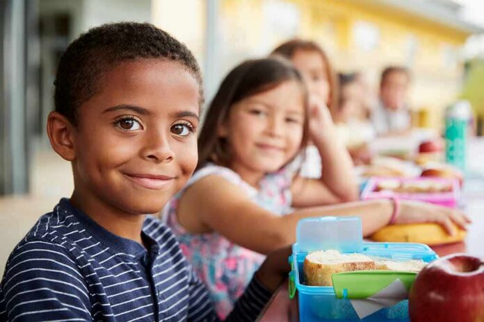 Smiling boy at a lunch table with classmates