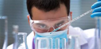 Scientist pipetting blue liquid into test tubes