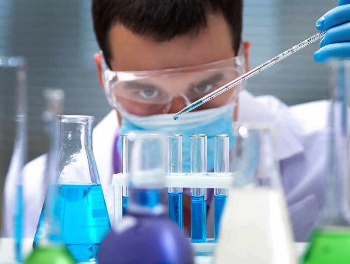 Scientist pipetting blue liquid into test tubes