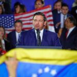 man in suit speaking at a podium during a rally