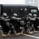 Tactical team advances beside an armored vehicle