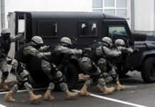 Tactical team advances beside an armored vehicle