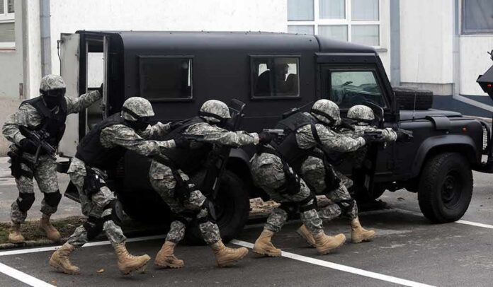 Tactical team advances beside an armored vehicle