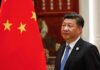 Xi Jinping standing beside a Chinese flag