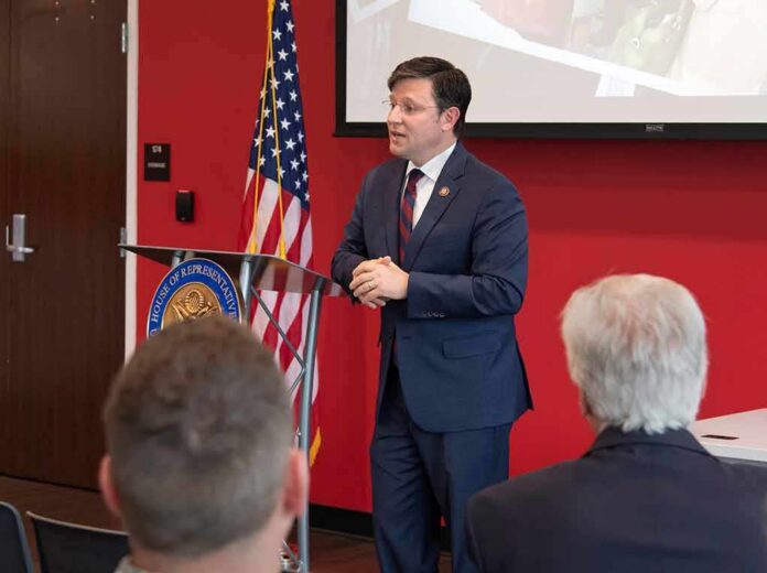 Speaker in a navy suit addressing an audience at a podium
