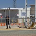 Security guard at chain-link gate of fenced facility