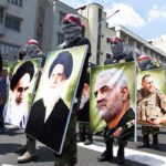 Masked Extremists Crash America 250 Protesters holding large portrait posters during a street march