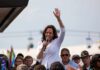 Kamala Harris speaking at outdoor rally, Paul Scholes in the crowd