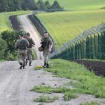 Soldiers patrolling along a rural border fence