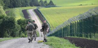 Soldiers patrolling along a rural border fence