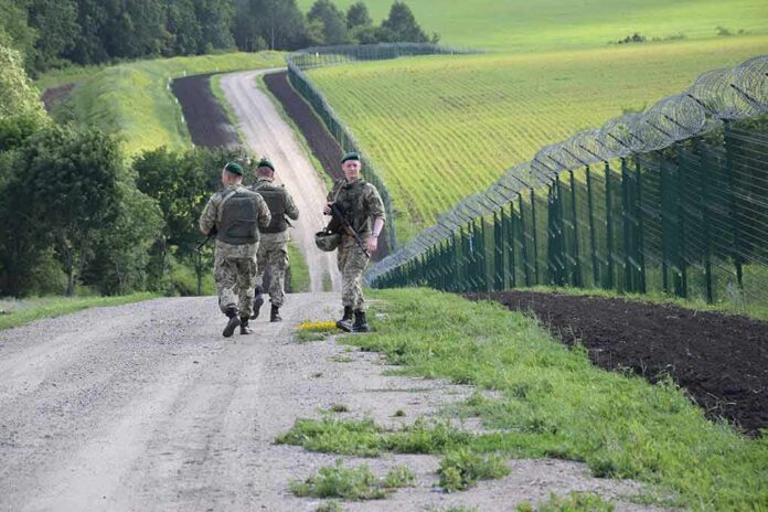 shutterstock_1481684600 Soldiers patrolling along a rural border fence