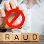 Person holding red prohibition symbol over wooden blocks spelling fraud