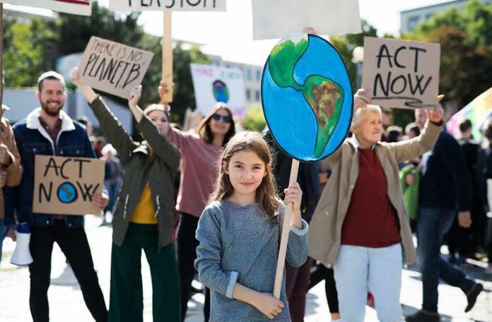 shutterstock_1513189952 Girl holding Earth sign at climate protest