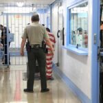 Killer Outrage Freezes Burnham’s Prison Plan Corrections officers escort an inmate in a jail hallway