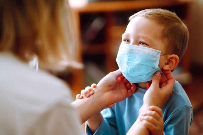 shutterstock_1685807257 child wearing a surgical mask being adjusted by an adult