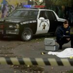 FBI agents examine a covered body at a taped-off crime scene
