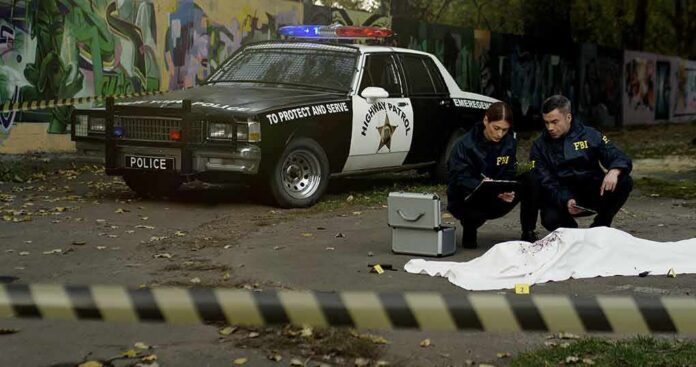 FBI agents examine a covered body at a taped-off crime scene