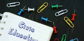 Notebook with civic education text and scattered push pins and paper clips