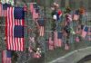 Ground Zero Showdown Erupts Memorial wall adorned with American flags and flowers