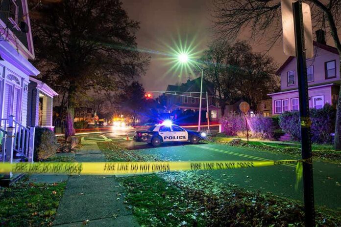 Police car blocks residential street at night behind caution tape