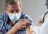 Older man in mask receiving a vaccine injection