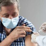 Tiny Vote Swing, Massive End‑Of‑Life Shock Older man in mask receiving a vaccine injection
