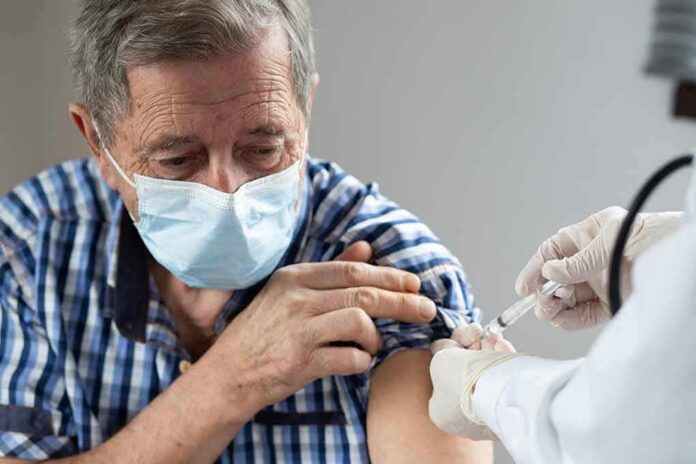 shutterstock_1893196456 Older man in mask receiving a vaccine injection